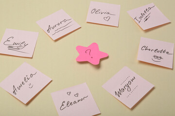 Choosing baby name. Paper stickers with different names and question mark on beige background