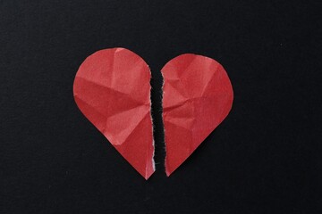 Halves of torn paper heart on black background, top view. Breakup concept