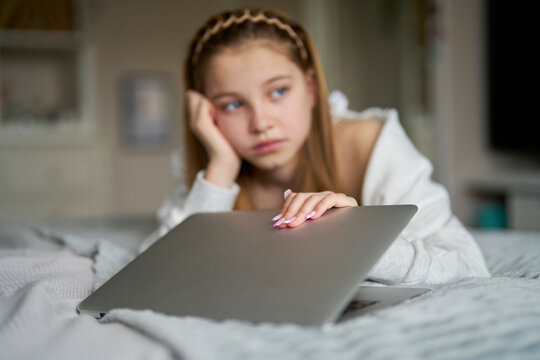 Unhappy Teenage Girl Closing Laptop Lying On Bed At Home Anxious About Social Media Online Bullying