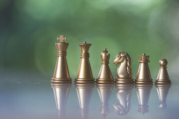 Sets of golden chess pieces on nature background. The photo of gold chess, king, rook, bishop,...