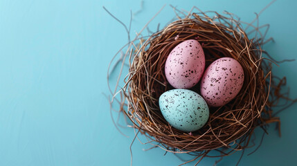 Fototapeta premium Easter blue and pink colorful eggs in a basket of twigs on a blue background, flat lay, copy-space