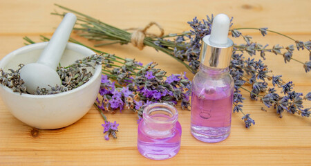 Obraz na płótnie Canvas Glass bottle of lavender essential oil on a wooden background.