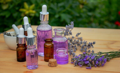 Obraz na płótnie Canvas Glass bottle of lavender essential oil on a wooden background.