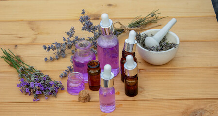 Glass bottle of lavender essential oil on a wooden background.