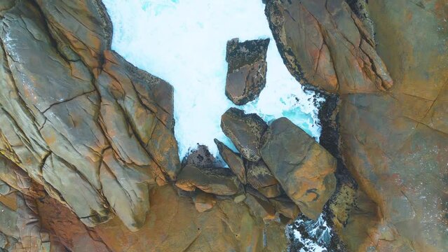 The ebb and flow of an outgoing tide against a rocky outcrop.