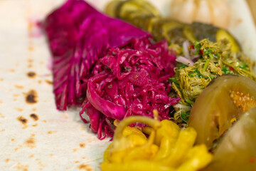 Pickled pickles on a tray with pita bread in close-up. Pickled cabbage with beetroot, johnjoli,...