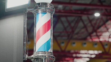 Classic barber pole with swirling red, white, and blue stripes in a shop setting
