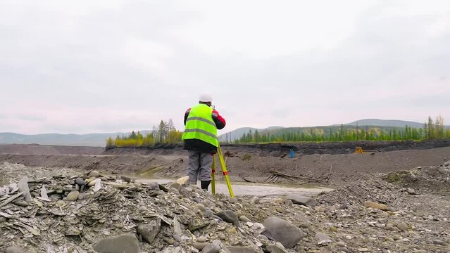 Surveyor Using Geological Tacheometer Equipment For Measuring Gold Mine. Surveyor Observes Industrial Gold Mine Location Through Tacheometer Equipment. Surveyor With Tacheometer Equipment At Mine
