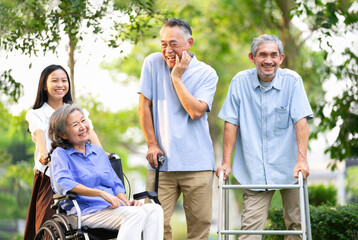 group of senior people with rehabilitation equipment enjoy talking together,a smiling teenager pushing a wheelchair for grandma,elderly asian friends spend their time in the park