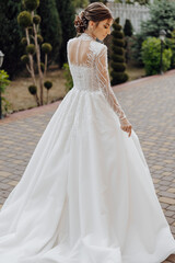 A woman in a white dress is standing on a brick walkway. She is wearing a necklace and a headband