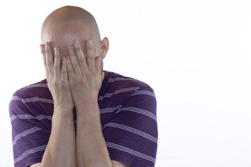 A bald man with depression covers his eyes with his hands and cries. Portrait of a 45-year-old man on a white background.