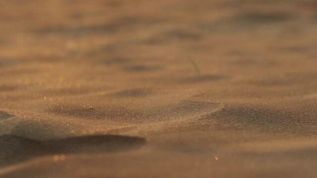 Small sand particles blowing over miniature dunes in slow motion