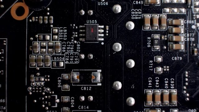 A close-up of the rear side of a graphics card reveals the PCB, a slender platform accommodating various chips and electronic elements. Connector interface.