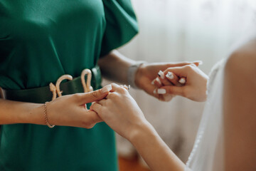 A woman in a green dress is giving a ring to another woman