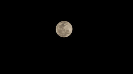 Bright moon shining in the dark night sky on a black background