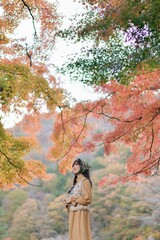 Asian woman in Japan's fall beauty, a cheerful holiday portrait in yellow and red foliage. A journey capturing the essence of nature, fashion, and casual elegance.