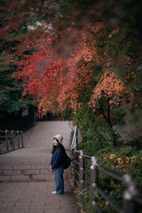 Asian woman in casual dress enjoys Japan's autumn in Kyoto. A cheerful holiday portrait capturing friends, smiles, and colorful foliage by the lake.