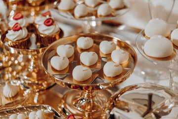 A table full of desserts, including cakes and cupcakes, with a gold tray in the middle