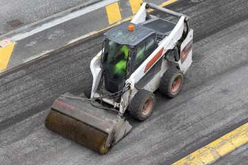 Aerial view of a sweeper machine at work during asphalt renewal on a city road