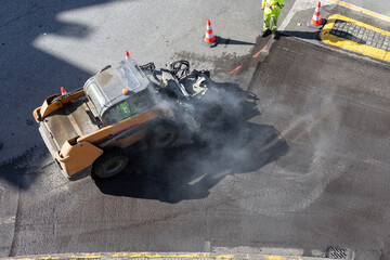 Aerial view of a sweeper machine at work during asphalt renewal on a city road