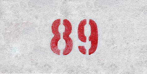 Red Number 89 on the white wall. Spray paint.