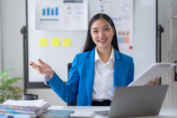 Beautiful young Asian business woman manager or company worker holding accounting document,...