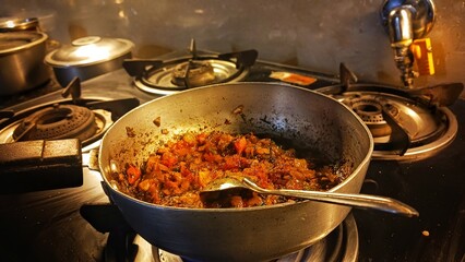 Traditional way of preparing indian masala for curry using gas pan. Picture of traditional India cuisine made of fresh ingredients in kitchen during dinner.
