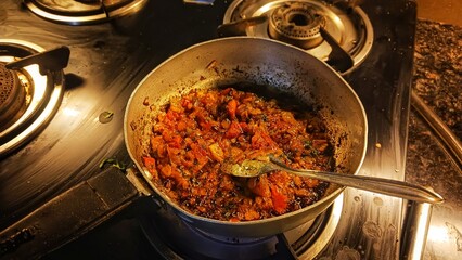 Traditional way of preparing indian masala for curry using gas pan. Picture of traditional India cuisine made of fresh ingredients in kitchen during dinner.