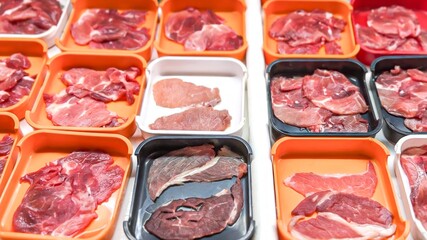 Array of fresh, raw fresh meat cuts neatly displayed in orange trays, offering a variety of choices...