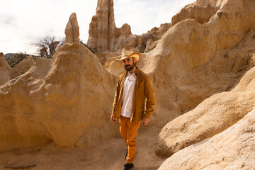 A man wearing a cowboy hat walks across a bridge in front of a mountain range. The scene is serene...