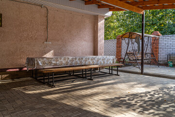 Large seating area with a long table and benches on the site near the country house with barbecue...