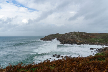 En automne, les fougères aux tons automnaux en premier plan, une mer agitée sous un ciel couvert à la Pointe du Millier, une atmosphère saisissante en Bretagne.