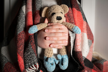 Blackout. Children's toy (teddy bear) in hands close-up. Power outages, destruction of energy...