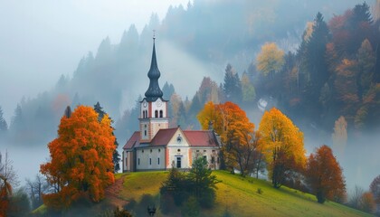 A beautiful church nestled in the rolling hills of Central Europe with soft morning mist and autumn foliage around it - obrazy, fototapety, plakaty