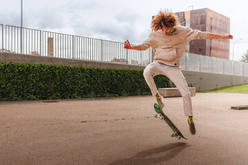 Active curly hair male skateboarding. Ollie trick. Copy space.