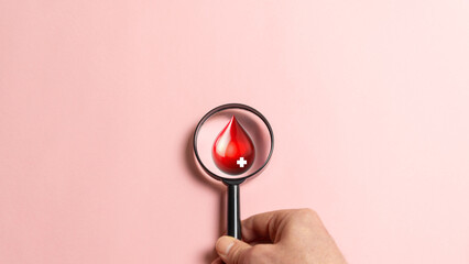 Magnifying glass with drop of blood, concept of world blood donor day.