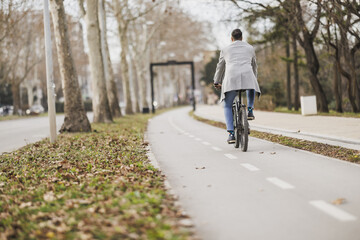 Man Riding Bicycle Down Tree-Lined Cycle Lane