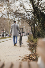 Man Walking Bicycle Down Sidewalk