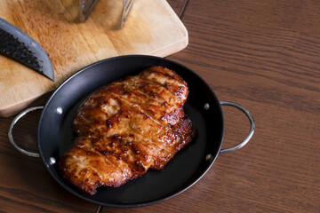 Fried pork in a pan on a wooden table