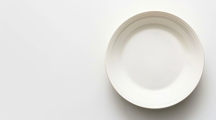   A white plate sits atop a table, adjacent to a knife and fork on a pristine white surface