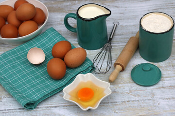 Backzutaten Eier, Milch und Mehl auf einem Küchentisch.	