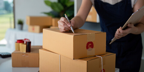 Woman in an online store check the customer address and package information on box. Online shopping...