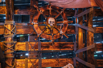 wooden steering wheel with a skull in captain's cabin on an ancient medieval pirate ship
