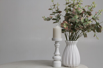 Flowers in a vase and a white candle on a white background