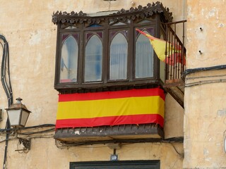 Weathered decaying balcony covered with spanish flag in Chinchon, Madrid community, Spain