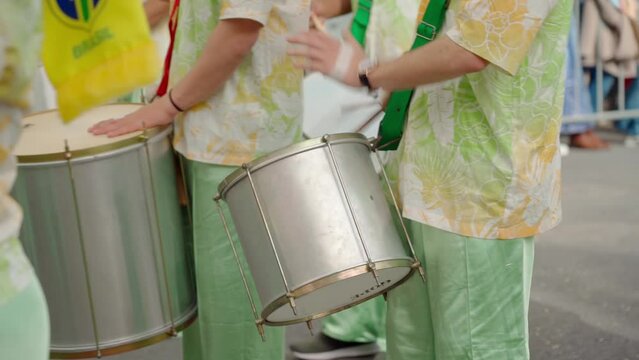 A group of drummers playing rhythmic sambo music during a carnival procession close-up dressed in traditional suits.