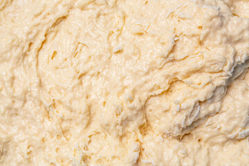 Macro selective focus raw dough texture backdrop. Texture of rolled dough. Background of the dough for baking. Fresh raw dough for pizza or bread baking. Close-up fermented doughs, homemade