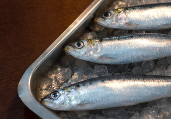 detail of three whole raw anchovies with ice
