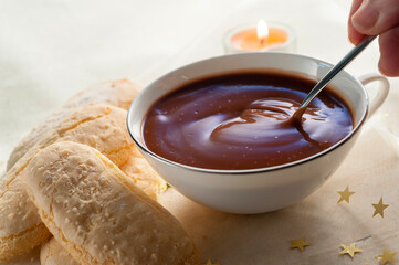hand stirring a spoon into a cup of hot chocolate
