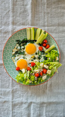 breakfast, plate with eggs with spinach, fresh cucumber, lettuce, tomatoes, no people, top view